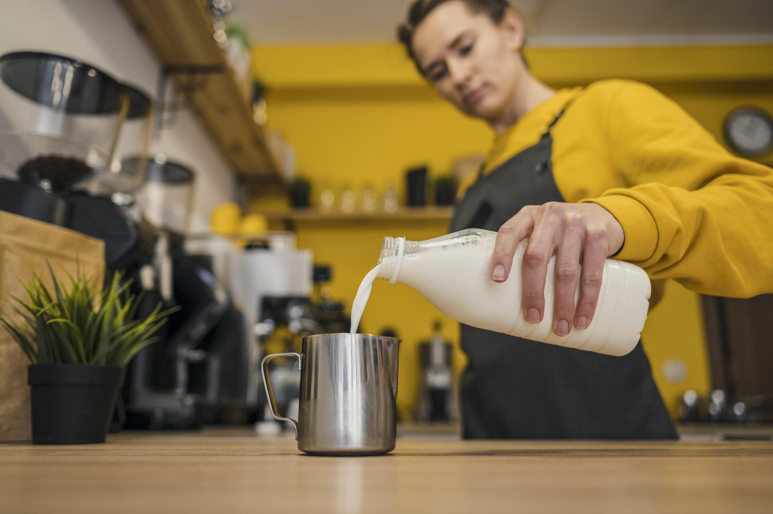 Pouring cold milk into a stainless steel milk pitcher